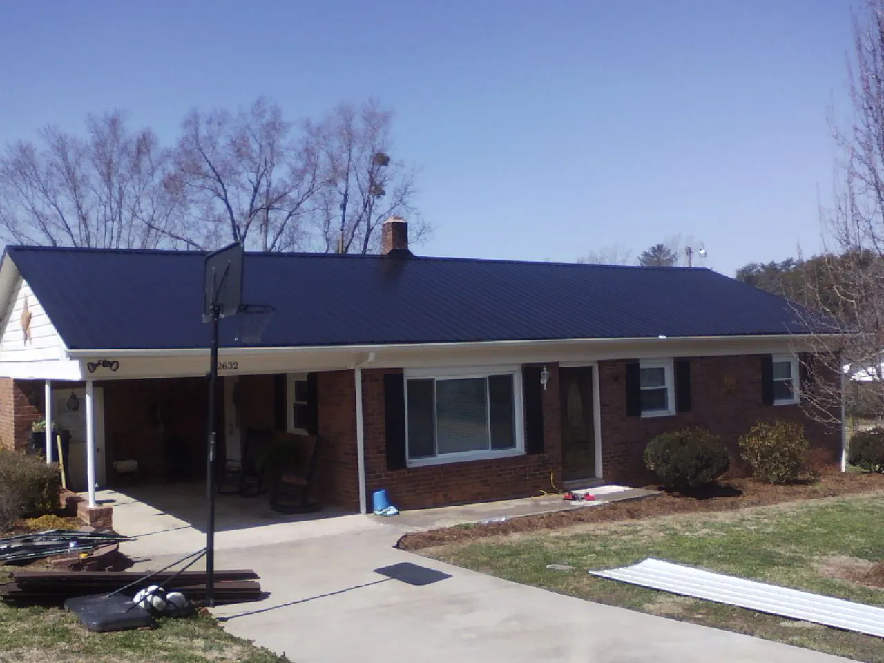 Finished dark blue metal roof on a brick ranch with a carport in Hillsdale