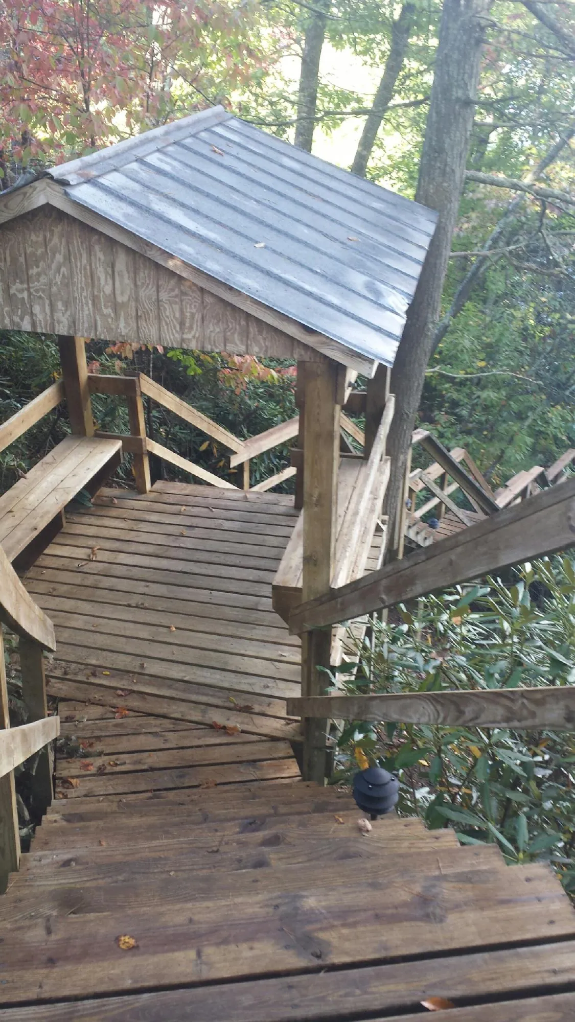 Metal roofed shelter over wooden steps on a wooded walkway — Skylight Repair & Installation work by our crew in Hillsdale