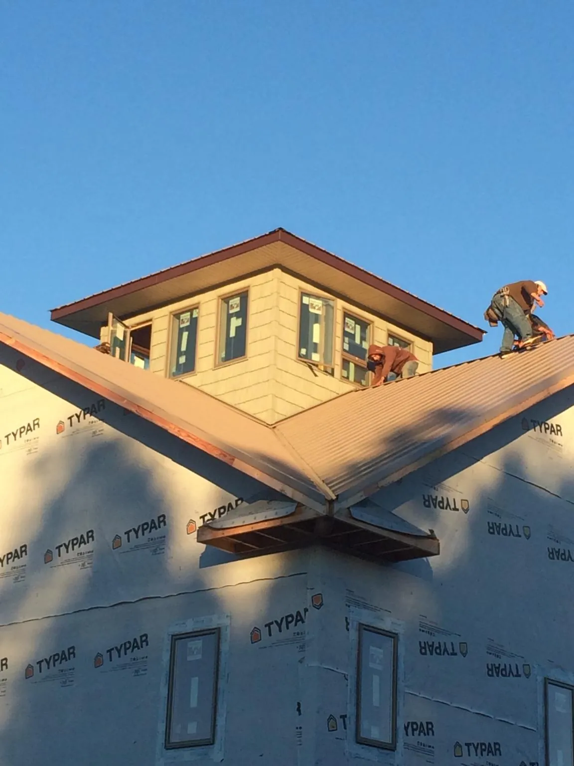 Roofers working around a rooftop cupola on a new metal roof at sunset — Roof Waterproofing in Hillsdale by Roofing Brothers